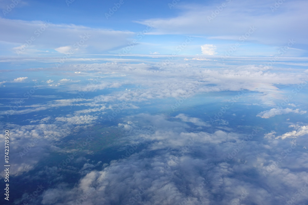 Fototapeta premium Beautiful white clouds drifting peacefully in the blue sky as seen from above or Layers of soft clouds stretching across the sky during a daytime flight.