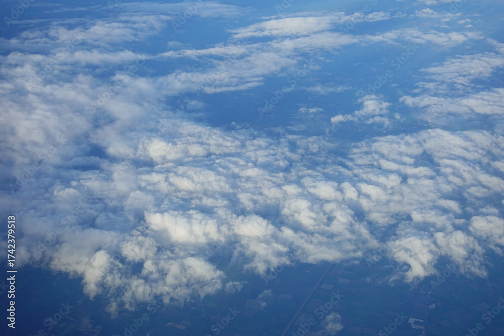 Fototapeta premium Beautiful white clouds drifting peacefully in the blue sky as seen from above or Layers of soft clouds stretching across the sky during a daytime flight.
