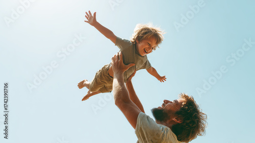 Father tossing happy son against clear blue sky