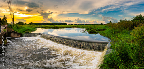 The evening sun at the dam slows down the water flowing through the weir.