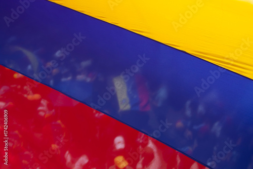Crowd and flag seen through the transparency of a Venezuelan flag.