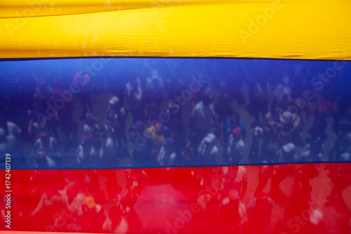A crowd seen through the transparency of a Venezuelan flag. A symbol of unity and civic expression.
