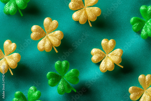 Pattern of gold and green shamrock shapes scattered on a textured green fabric background. The image evokes a festive and decorative atmosphere, suitable for St. Patrick's Day.