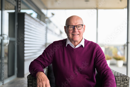 Portrait of happy senior man smiling at the camera while sitting outdoors