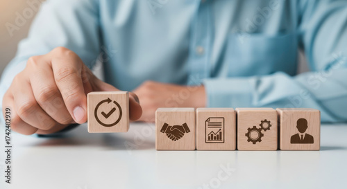 Hand arranging wooden blocks with business icons representing workflow success