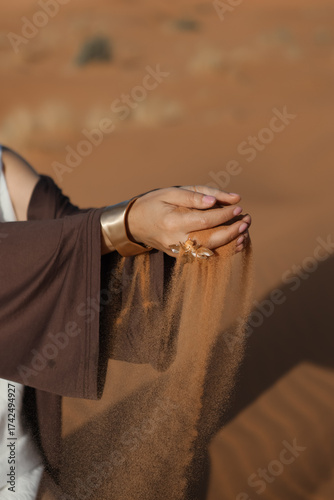 beautiful hands with jewelry are sprinkling fine desert sand