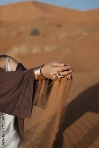 A woman's hands with a beautiful ring, and yellow desert sand spilling from them