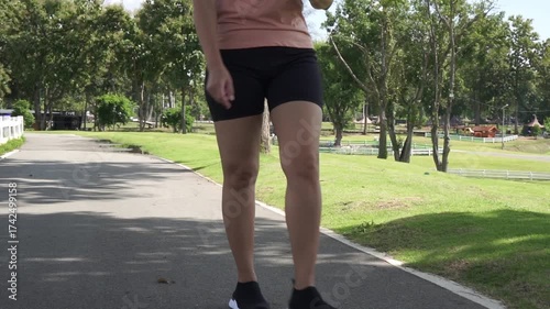 Asian woman walking for exercise and relax on path in the park . Slow motion.