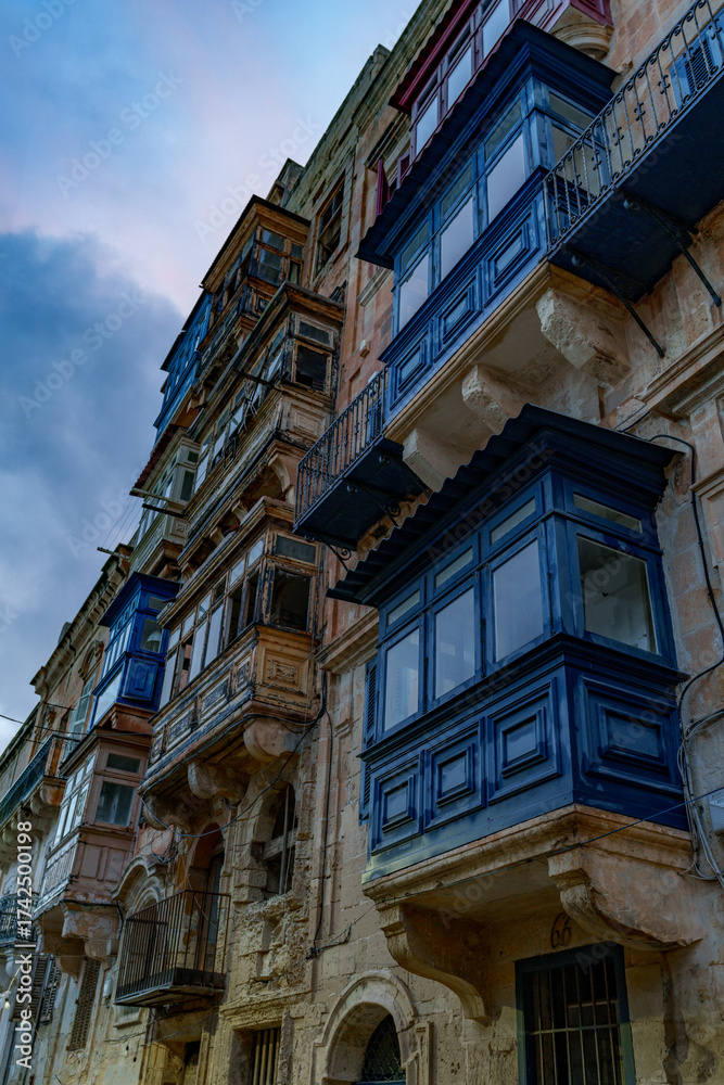 Obraz premium Upward View of Traditional Maltese Enclosed Balconies against Blue Evening Sky