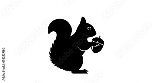 Black silhouette of a squirrel holding an acorn.