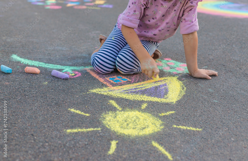 Fototapeta premium Children drawing with chalk on the asphalt. Selective focus.