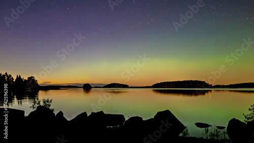 Amazing aurora borealis dancing over calm lake in >Farnebofjarden national park in  north of Sweden.