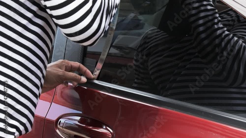 Close up of thief breaking into car using metal tool, symbolizing crime, car theft, security risk, and importance of vehicle protection, police awareness, and personal safety concept