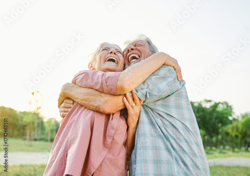Obraz na płótnie Happy active senior couple having fun talking and hugging in park outdoors