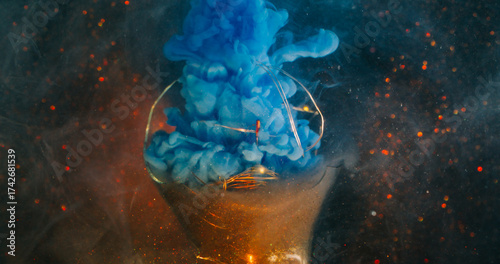 Haze flow blur. Broken light bulb. Color vapor spill on orange flare garland. Blue fume paint swirl on glitter abstract black background.