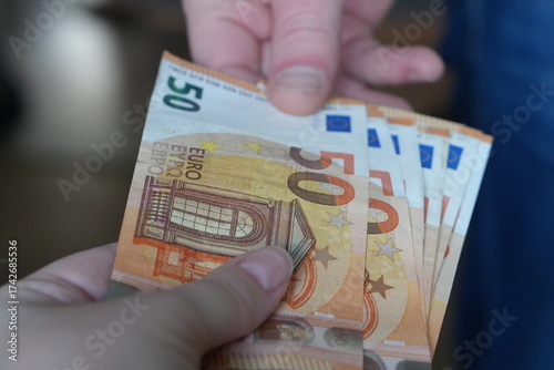 Close-up of a Financial Transaction: One Person Handing Over Multiple €50 Euro Banknotes to Another, Symbolizing Payment and Exchange