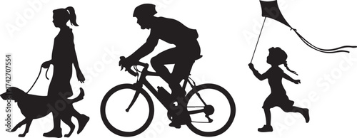 Silhouette of people walking dog cycling and flying kite