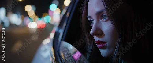 Pensive woman gazing from car window at night city lights