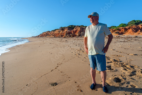 Hombre mayor en la playa mirando al mar con una sonrisa. Enfoque selectivo y espacio para texto.