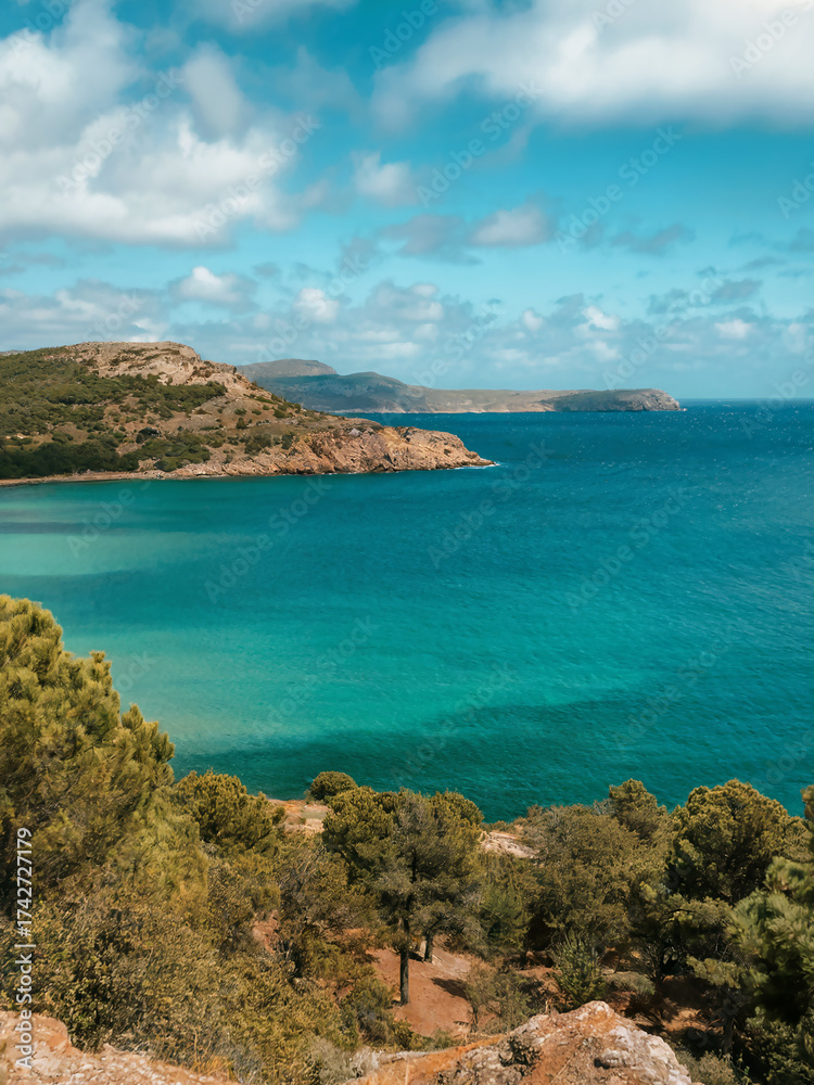 Fototapeta premium Scenic coastal view with turquoise waters and rugged cliffs under a blue sky.