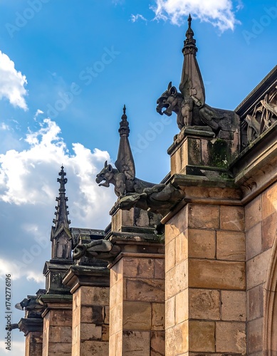 Gothic architecture detail with gargoyles and spire against blue sky