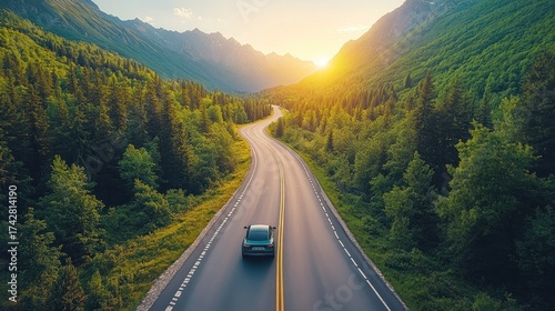Scenic road winds through lush mountain valley at sunset