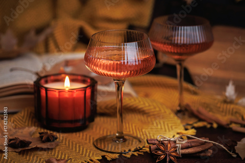 Textured rose wine glass with candle and spices on yellow blanket in warm fall setting