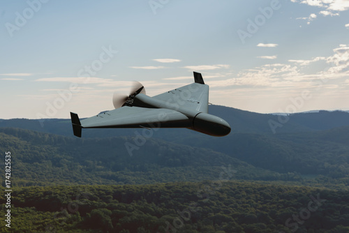 A military kamikaze drone flies over forested mountains in the evening.