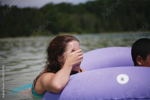 Woman on lake covering her face while on a tube in a lake in Michigan 