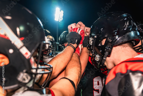 Obraz na płótnie American football team staying motivated during night huddle