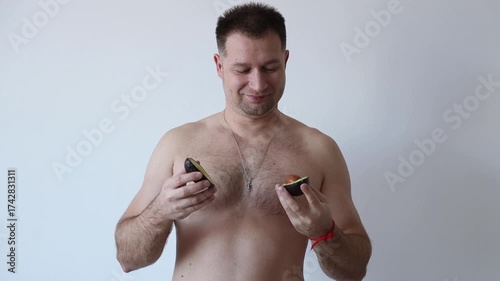 Man with bare torso holding an avocado. A guy's daily routine