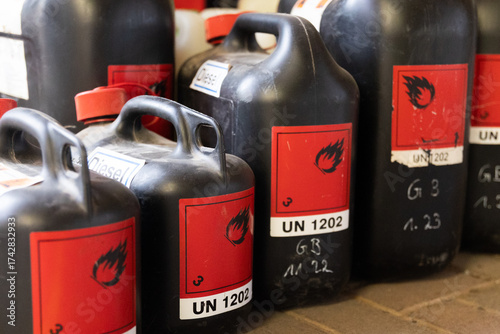 Mehrere schwarze Chemikalienkanister mit Gefahrstoffkennzeichnung stehen geordnet in einer industriellen Umgebung. Das Motiv steht für Gefahrgut, sichere Lagerung und professionelle Handhabung von Che