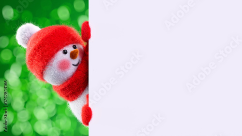 Playful wool‑felt snowman pops in from the right beside a blank banner, red hat and mittens glowing on a soft green bokeh backdrop. 3d render illustration.