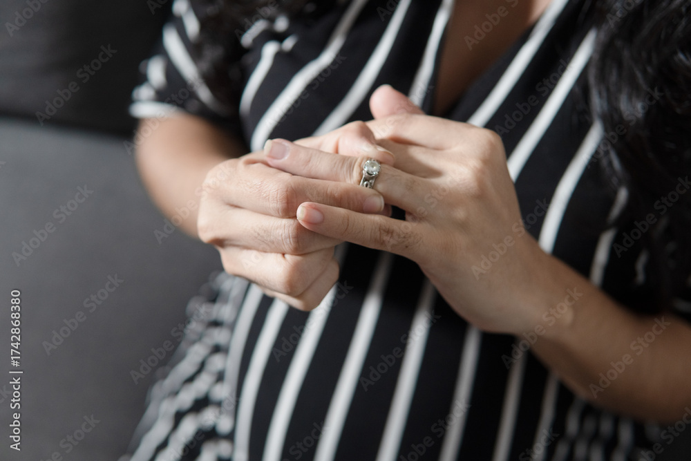 Fototapeta premium Woman contemplating divorce removing wedding ring