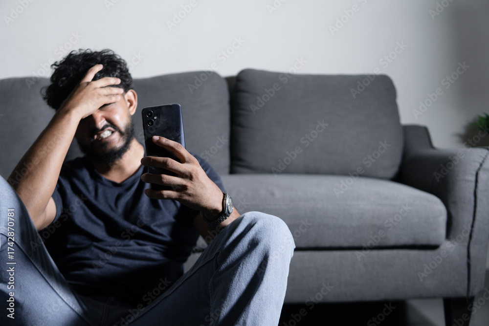 Fototapeta premium Stressed man feeling frustration using phone at home