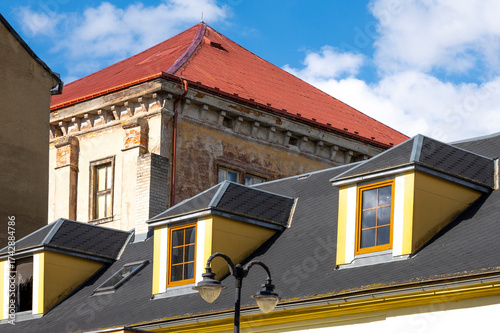 Fotografía contrast of renovated modern roof with dormer windows and old weathered historic