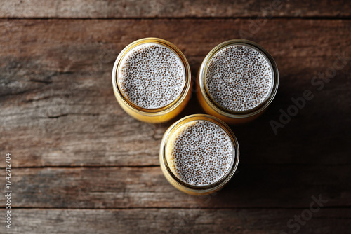 Overhead shot of three jars filled with vibrant chia seed pudding on rustic wood. Represents healthy eating, trendy diets, and natural lifestyle concepts.