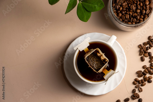 Drip bag of fresh drink in a glass with coffee beans. Drip coffee using a paper type filter.