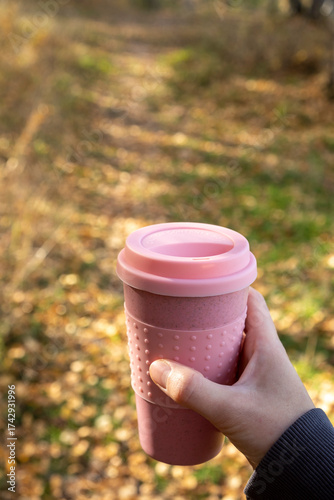 Woman holding cup of coffee in autumn park