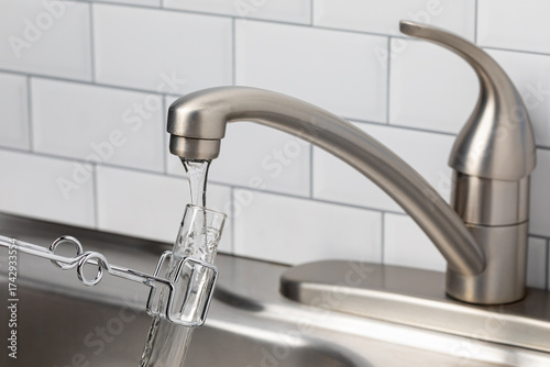 Testing tap water from faucet. Drinking water contamination, plastic pollution and water quality concept.