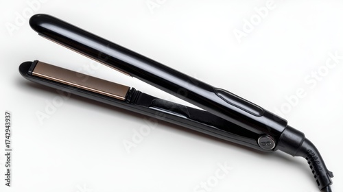 a black flat iron with a sleek design. it's resting on a clean white surface, and its cord is curled neatly alongside it, ready for use