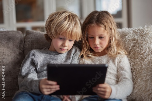Siblings relaxing at home watching a movie on a tablet