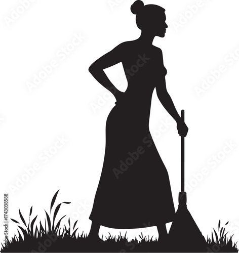 Silhouette of woman in long dress holding broom standing in grass