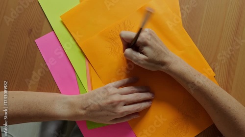 Video of young woman draws of colorful papers in the room at day time