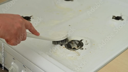 Person scrubbing white stove with brush