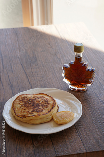 白い皿に乗ったパンケーキとメープルシロップ