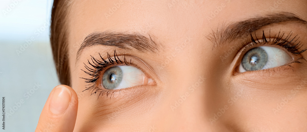 Naklejka premium Beautiful young woman putting in contact lenses at home, closeup