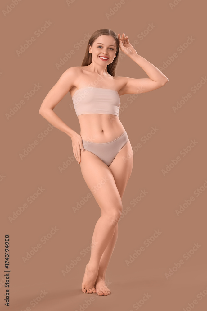 Naklejka premium Beautiful happy young woman in underwear on beige background