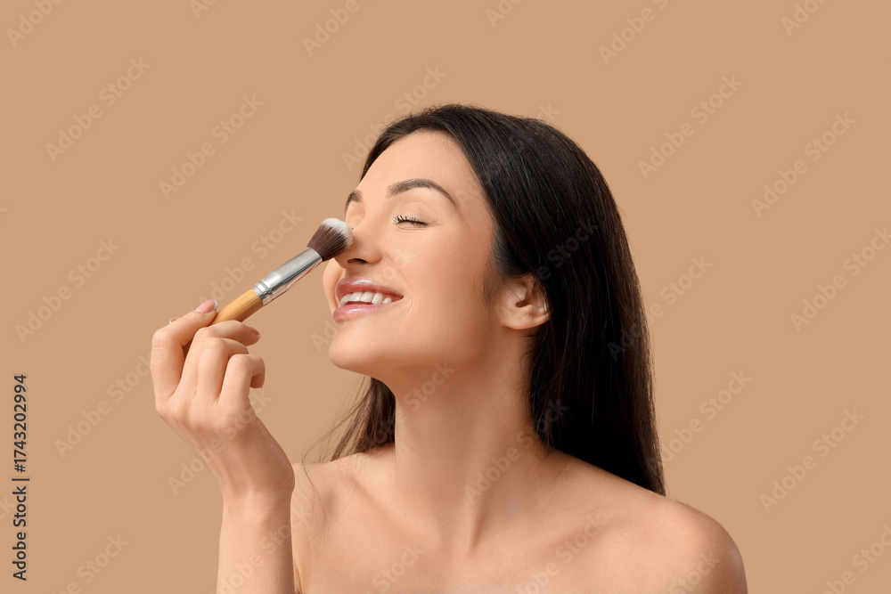 Obraz premium Beautiful young woman with makeup brush on brown background