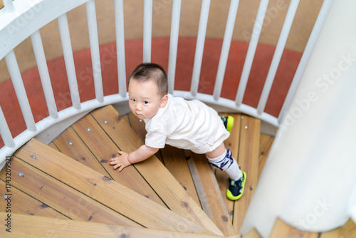 A young Asian boy practising crawling in an outdoor playground.